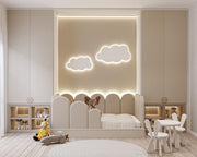 Children's bedroom with a bed, toys, and wall lights shaped like clouds.